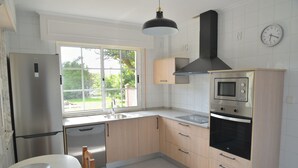 Una cocina moderna con refrigerador de acero inoxidable, lavavajillas, horno empotrado y ventana que proporciona luz natural.