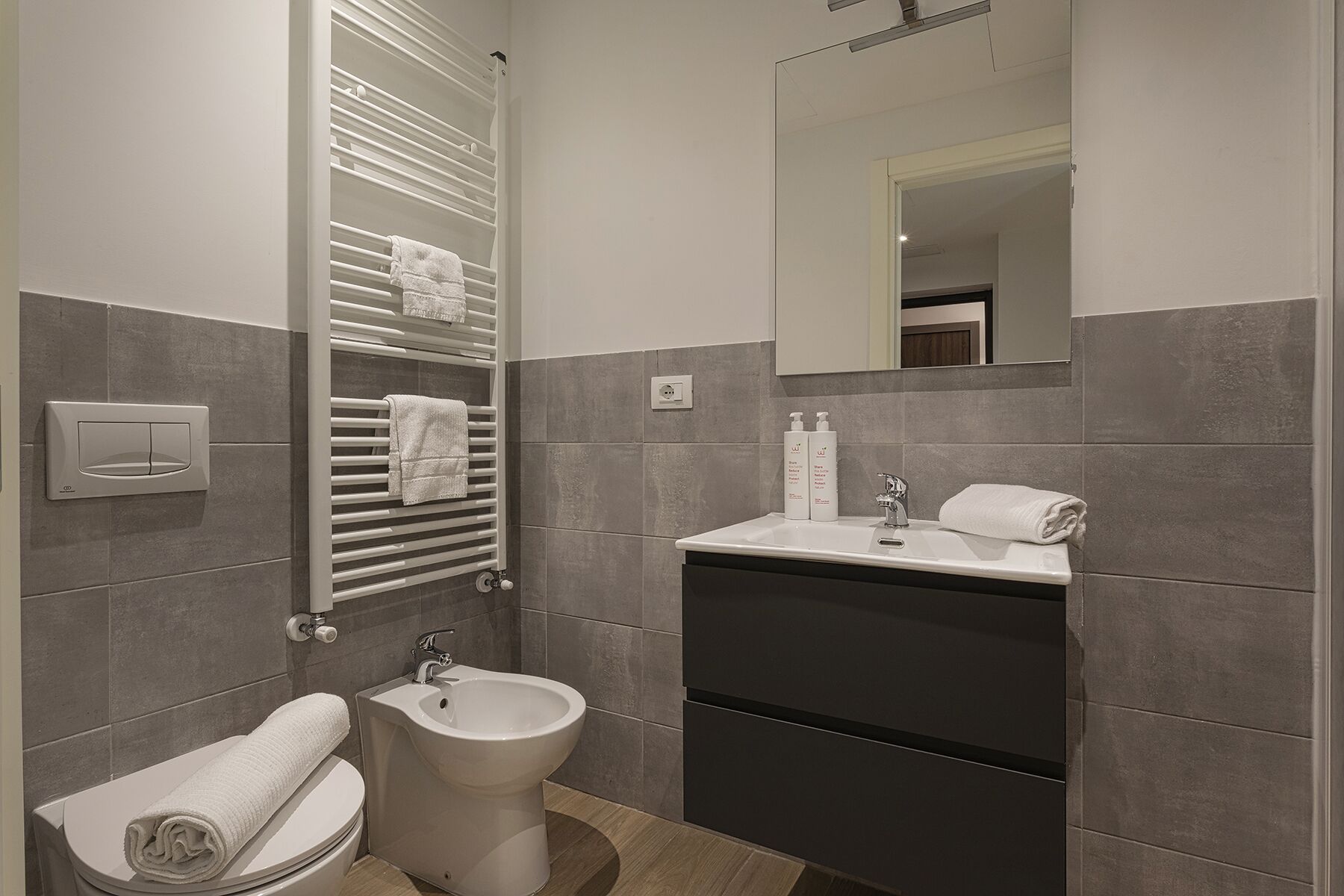 A modern bathroom with a bidet, toilet, and sink.