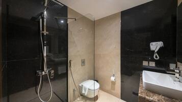 A modern bathroom with a glass-enclosed shower, a toilet, a hairdryer, and a sink.