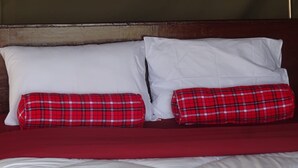 A bed with white and red bedding, two white pillows, and two red plaid pillows.