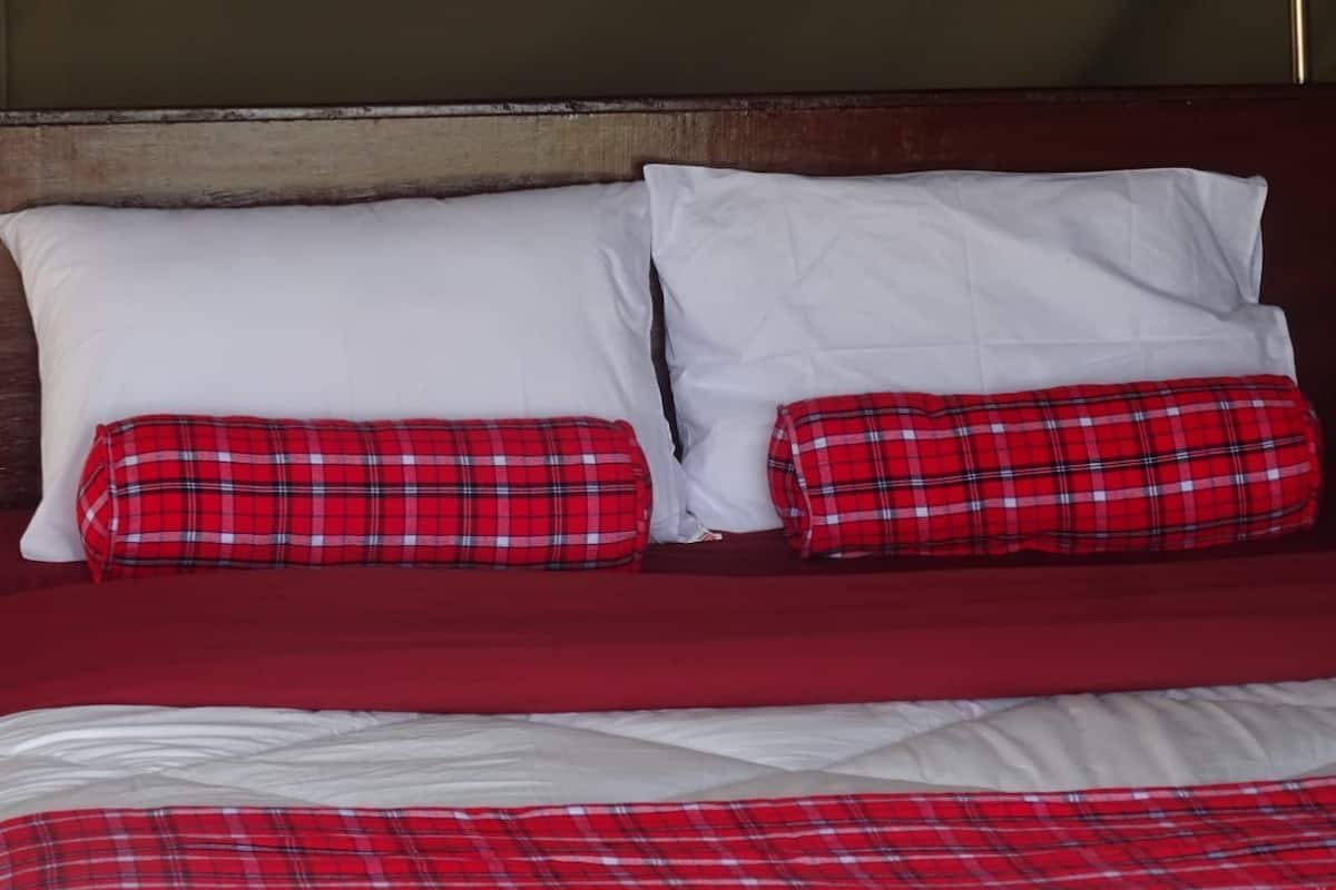 A bed with white and red bedding, two white pillows, and two red plaid pillows.