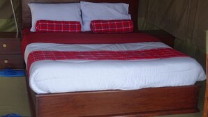 A single bed with a wooden frame, white bedding, and red and white plaid pillows.