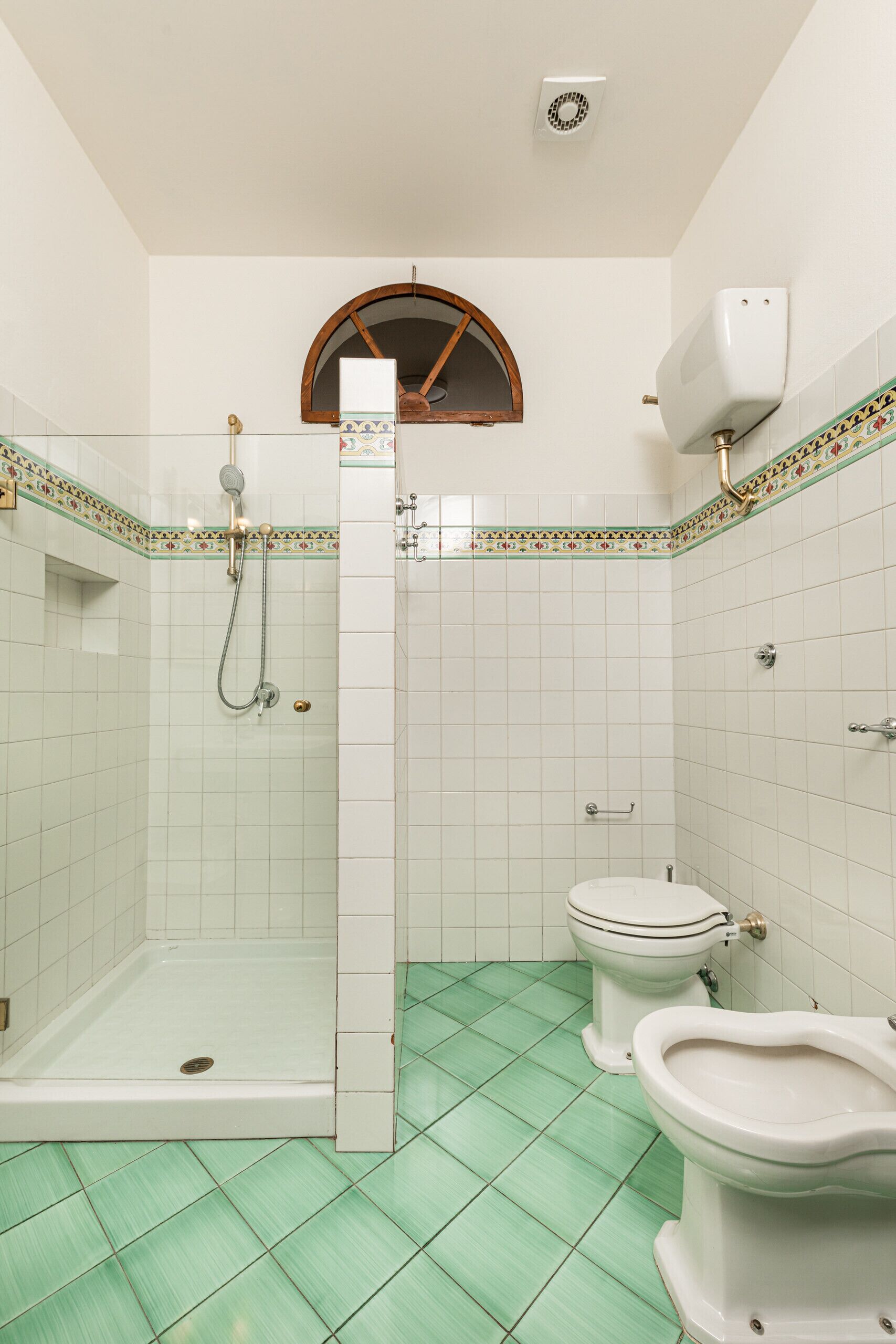 A bathroom with a shower, toilet, and bidet.