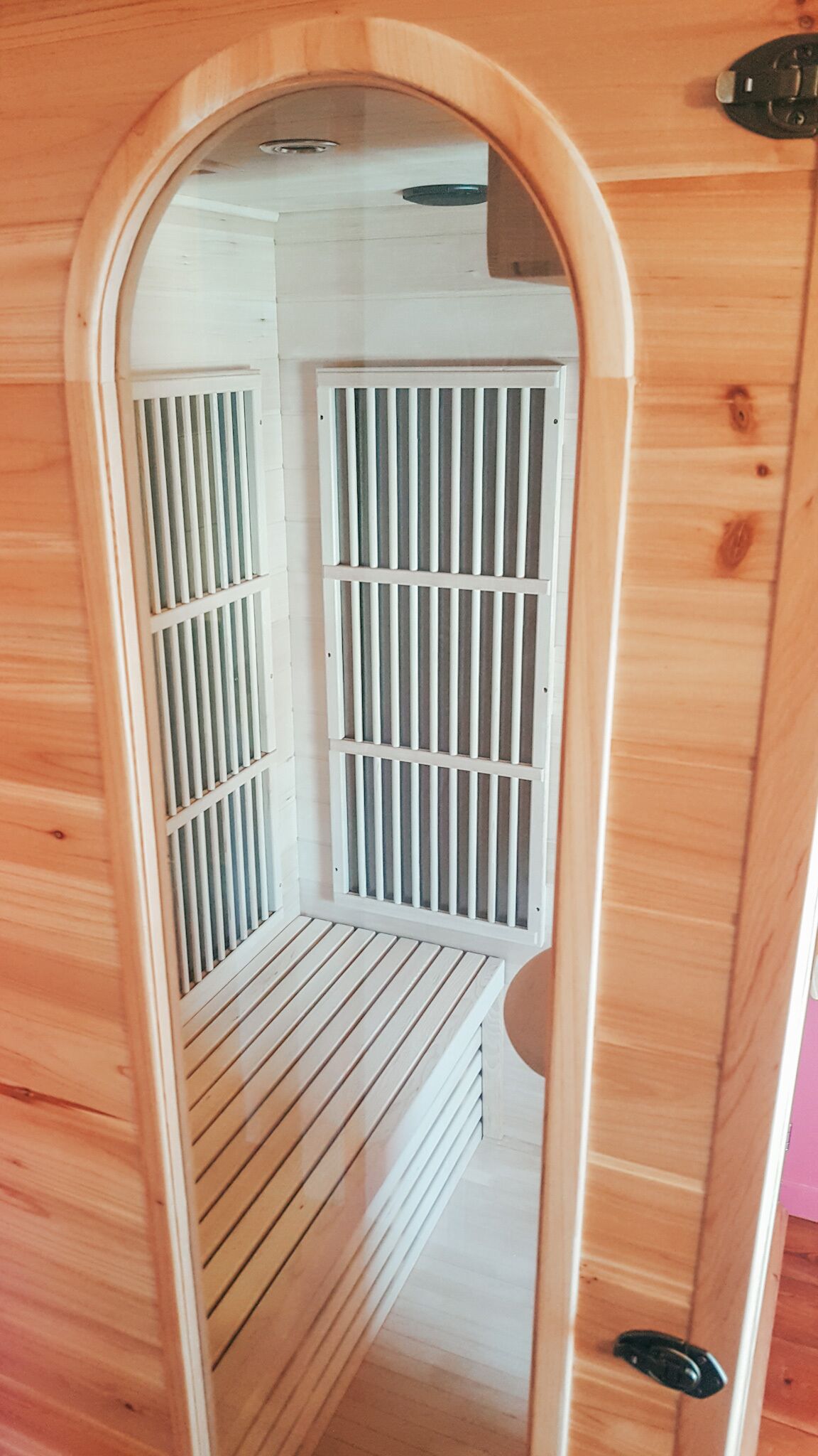A wooden interior with a mirrored wall, a white ceiling, and a door with a black handle.