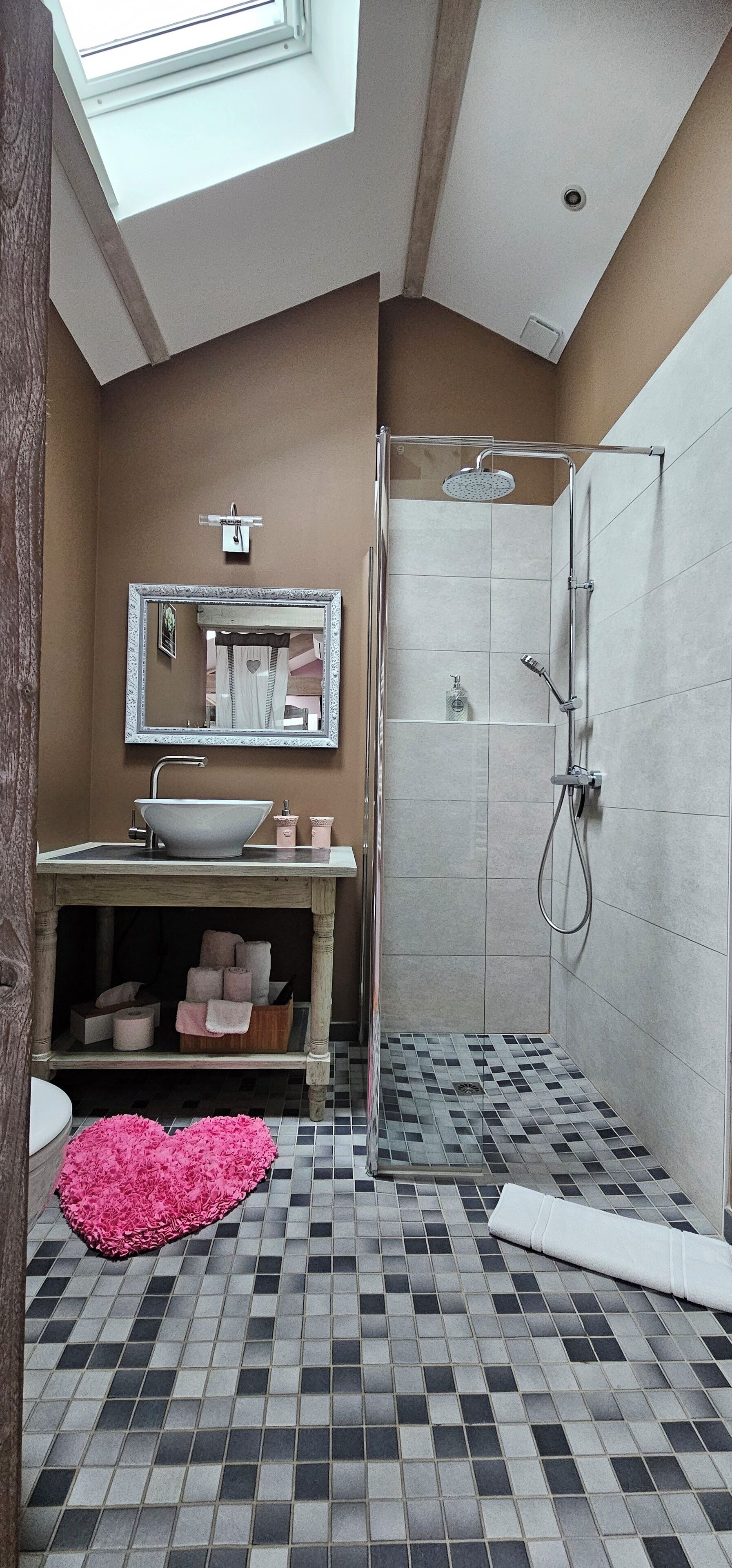 Un baño con tragaluz, un lavamanos con recipiente grande, un espejo, ducha y suelo de baldosas.
