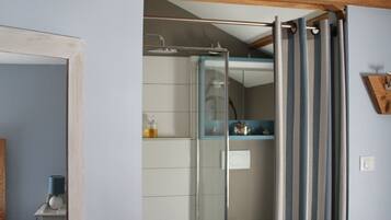 Een badkamer met een douche, toilet en spiegel.
