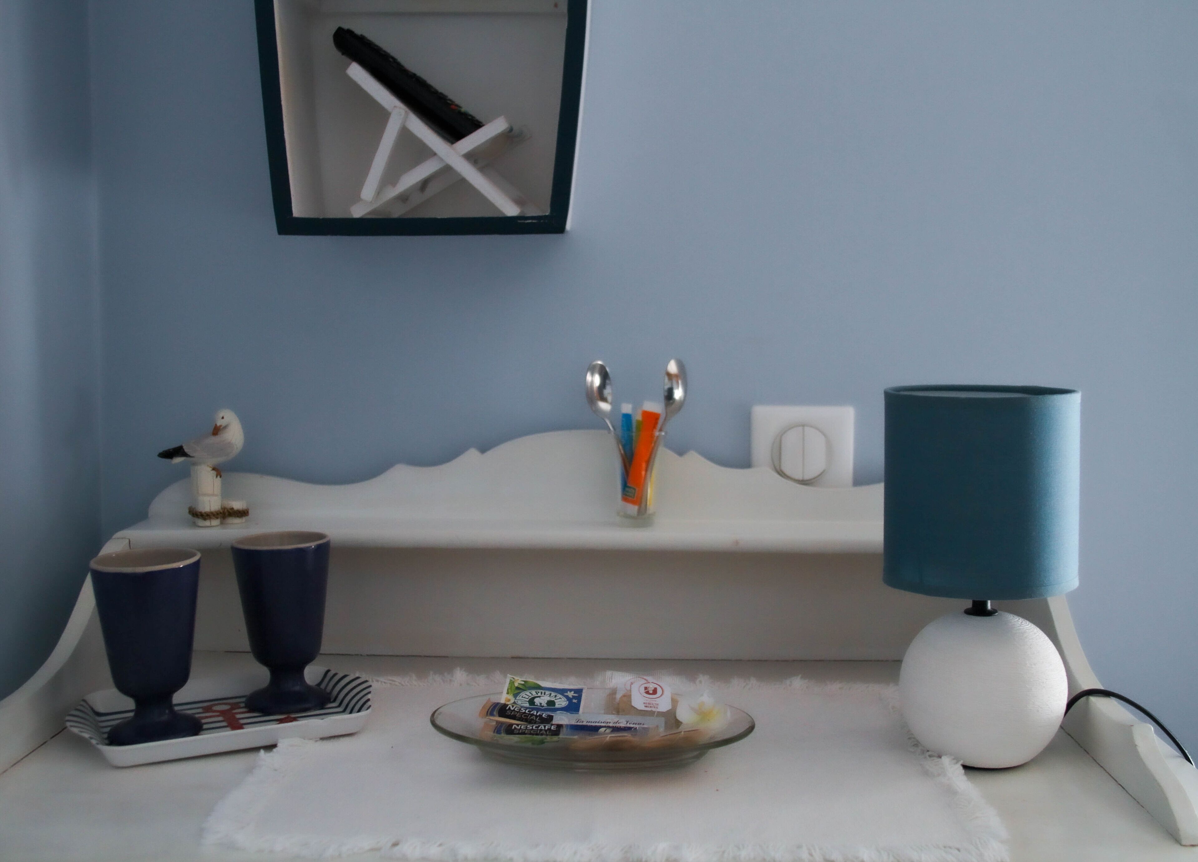 A bathroom with a white sink, a blue lamp, and a framed picture on the wall.