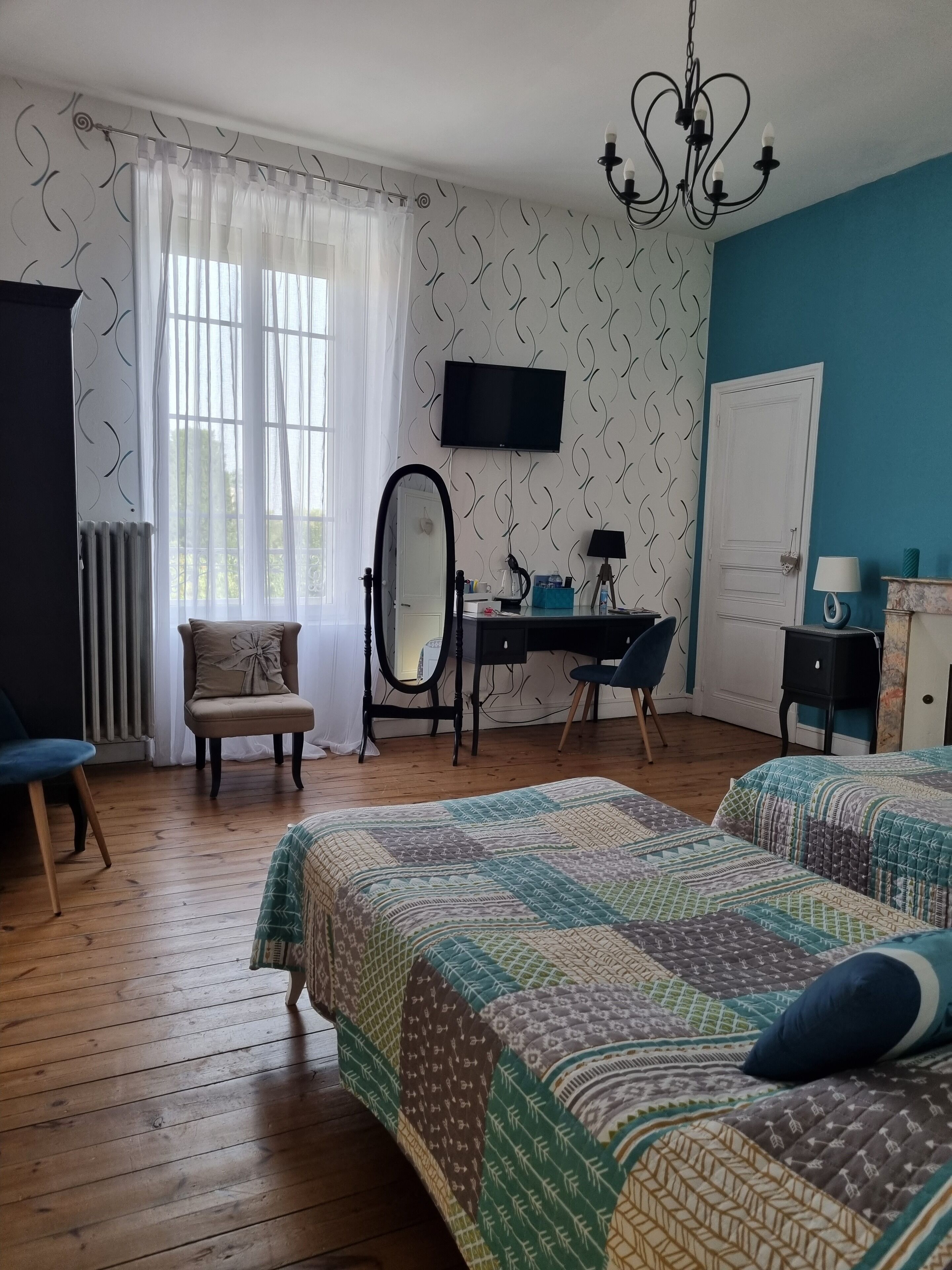 Un dormitorio con dos camas, un escritorio, una silla, un espejo, un televisor y un radiador.