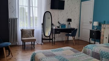 Un dormitorio con dos camas, un escritorio, una silla, un espejo, un televisor y un radiador.