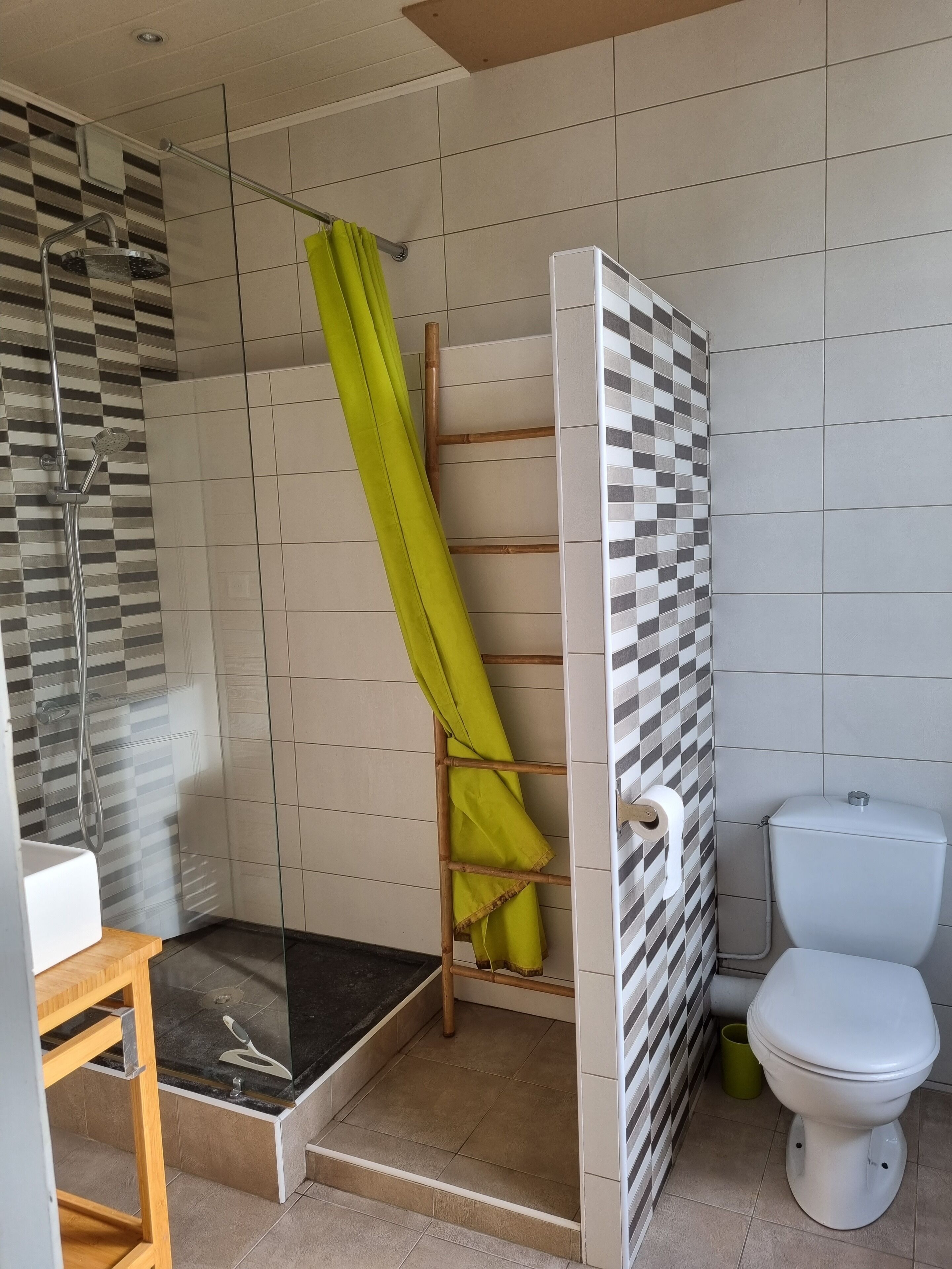 Ein Badezimmer mit Dusche, Toilette und Ablagefläche mit Handtuch.