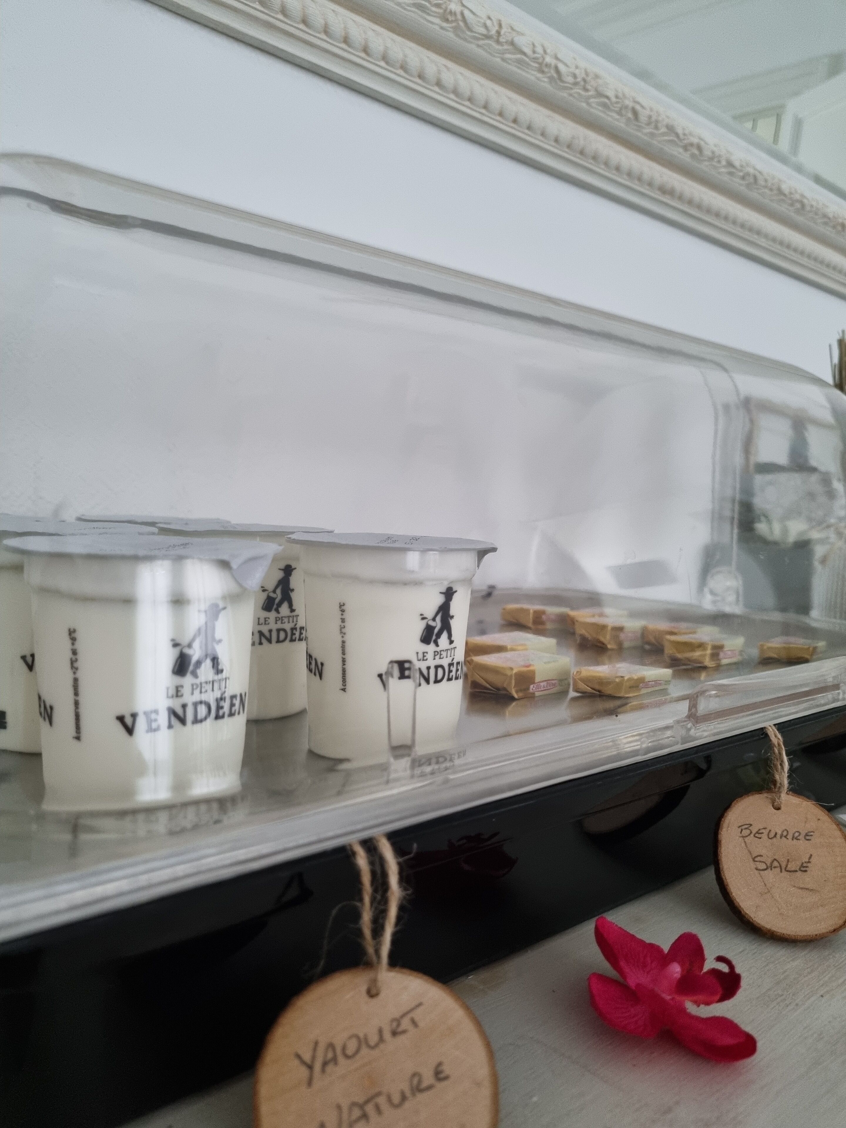 A display case with containers labeled "Le Petit Vendéen" and a wooden sign indicating "Yauourt Nature" and "Beurre Sale".