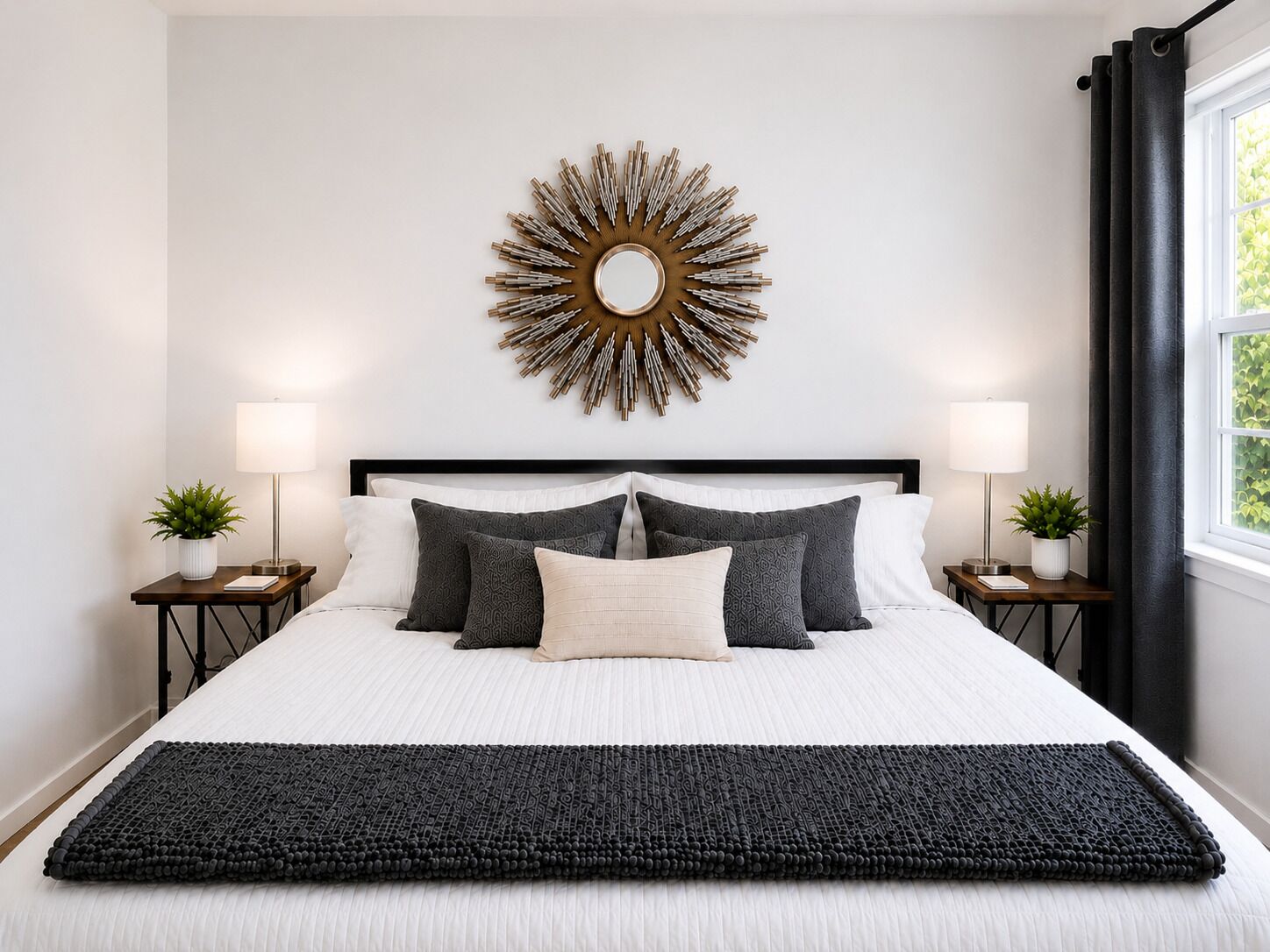 A neatly made bed with a white duvet and multiple pillows, flanked by two bedside tables with lamps and small potted plants.