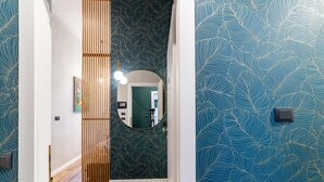 A hallway with a wooden slat partition, a round mirror, and a patterned wall.