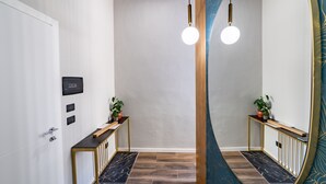 A modern hallway with a wooden console table, a potted plant, and a mirror reflecting the space.