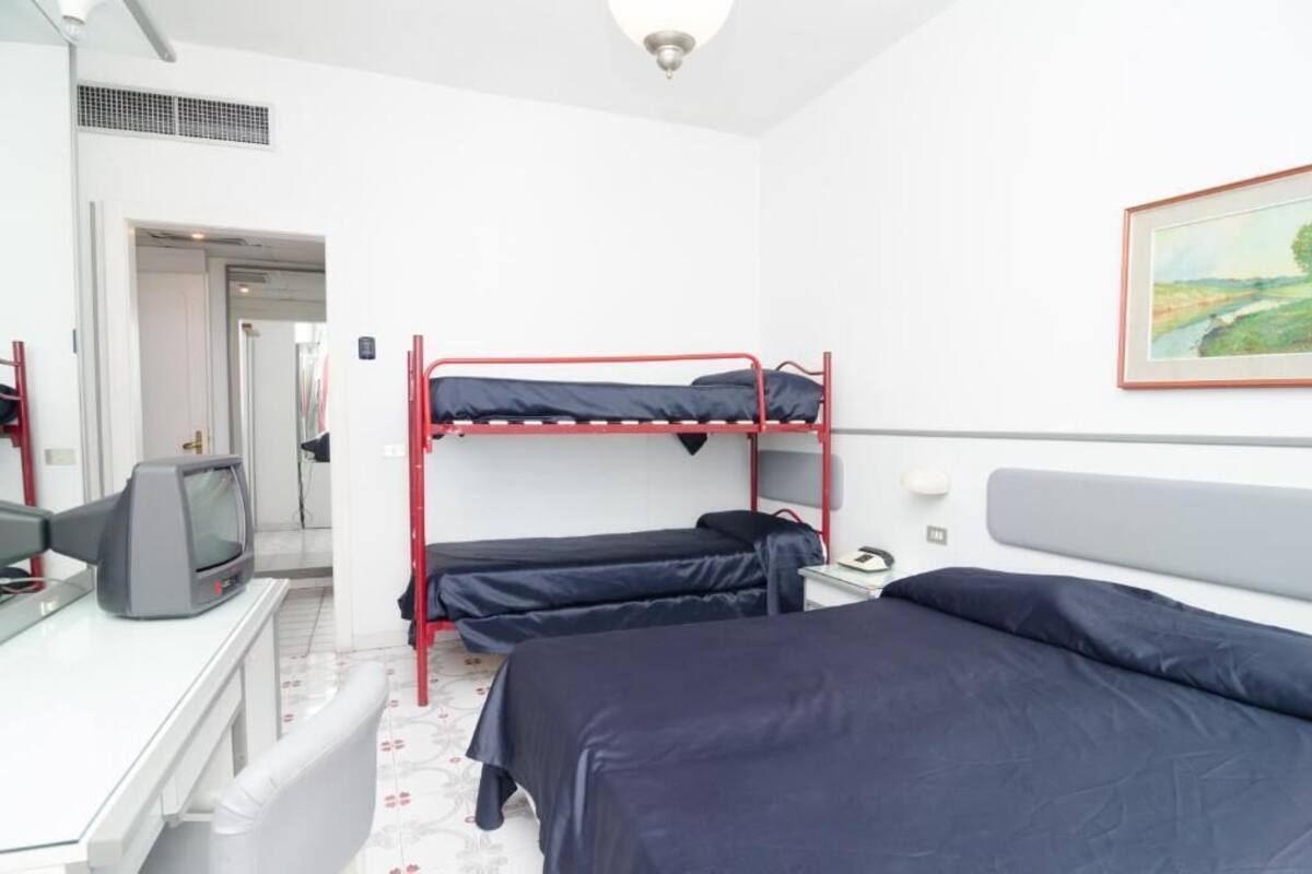 A room with bunk beds, a desk with a television, and a framed painting on the wall.