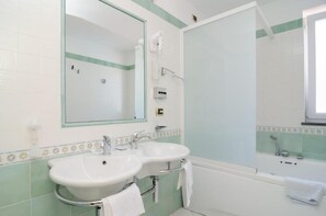 A bathroom with two sinks, a mirror, and a bathtub. - Hotel Flora Wellness & Beauty (Ischia)