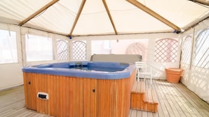 Un jacuzzi dentro de una tienda de campaña con una terraza de madera y una silla.
