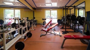Un gimnasio con equipo de levantamiento de pesas, bancos y un espejo grande.