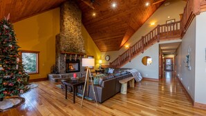 A spacious living area with a stone fireplace, wooden ceiling, and a staircase leading to an upper level. - Spacious Cabin w/Hot Tub~2 King beds, fire pit (Slatyfork)