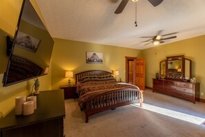 Ein Schlafzimmer mit Bett, Kommode, Spiegel und Deckenventilator.