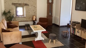 Un salon avec un canapé, un fauteuil, une table basse et une horloge au mur.