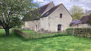 Un bâtiment en pierre avec une porte rouge et une clôture en bois.