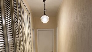 A narrow hallway with a door at the end, flanked by a row of closed louvered closets. - Appartement en Face de la Gare Routière de Menton (Menton)