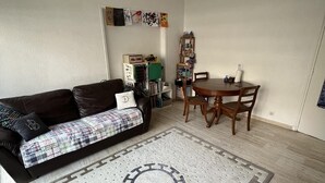 A living room with a sofa, a dining table, and a patterned rug. - Appartement en Face de la Gare Routière de Menton (Menton)