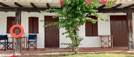 A building with a tiled roof, wooden doors labeled B16 and B15, and a tree with pink flowers in the foreground.
