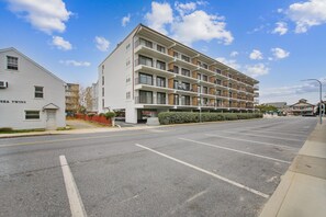 A multi-story residential building with a parking lot in front. - XPLORIE ACTIVITIES & LINENS INCLUDED*! Sunchaser - 2BR Condo on 36th St & Ocean Block! (Ocean City)