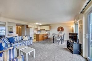 Un espacio habitable compacto con sofá, mesa de comedor, zona de cocina y televisor.