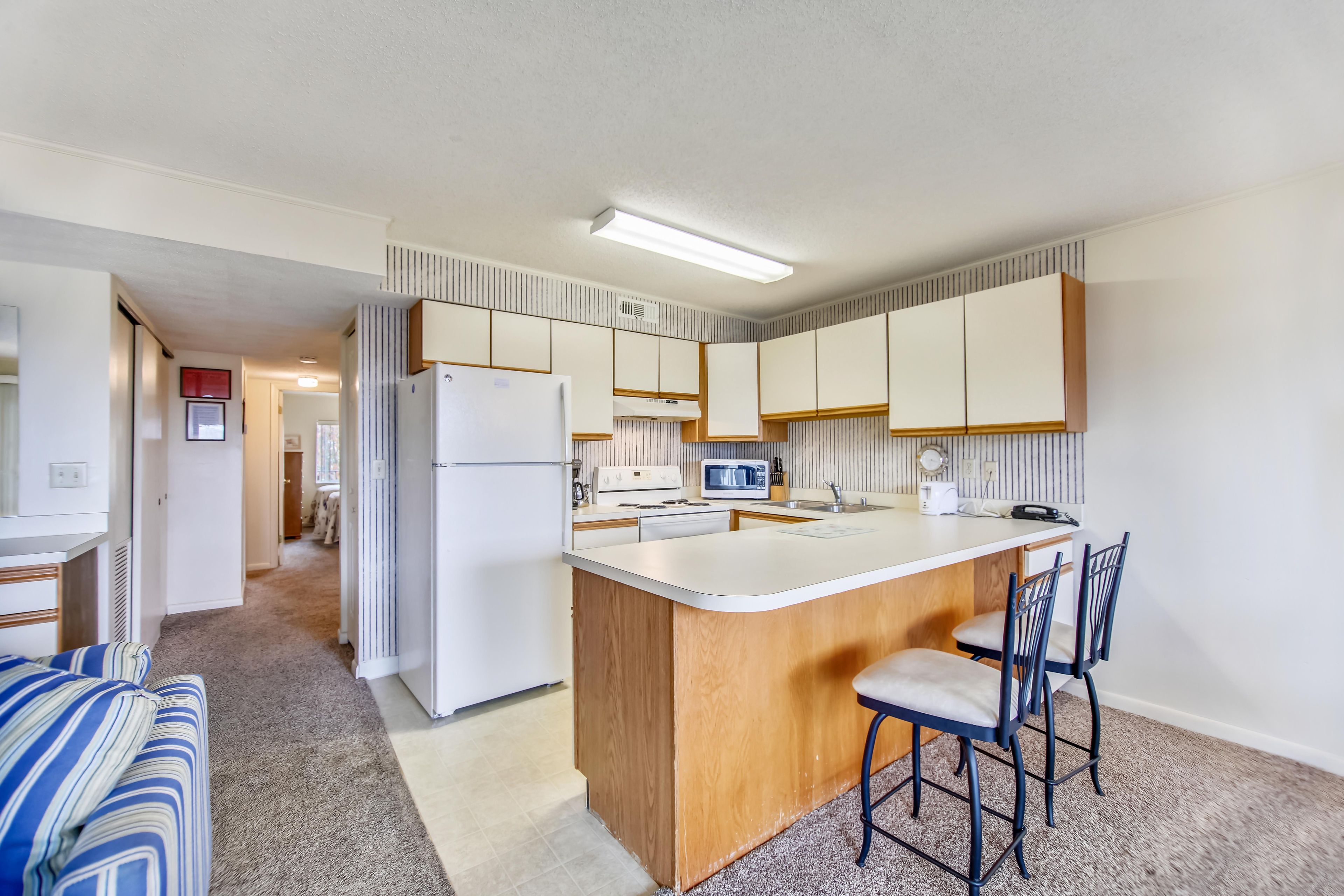 A compact kitchen with a central island, a microwave, and a refrigerator.