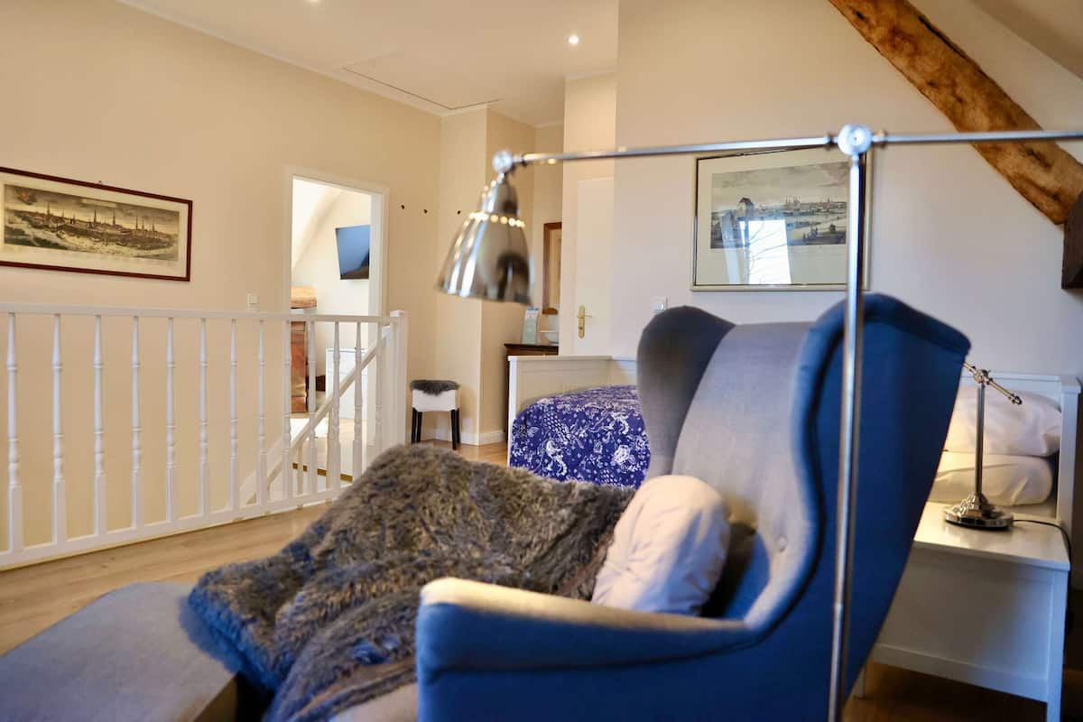 A bedroom with a bed, a bedside table, a lamp, and a view of the outside.