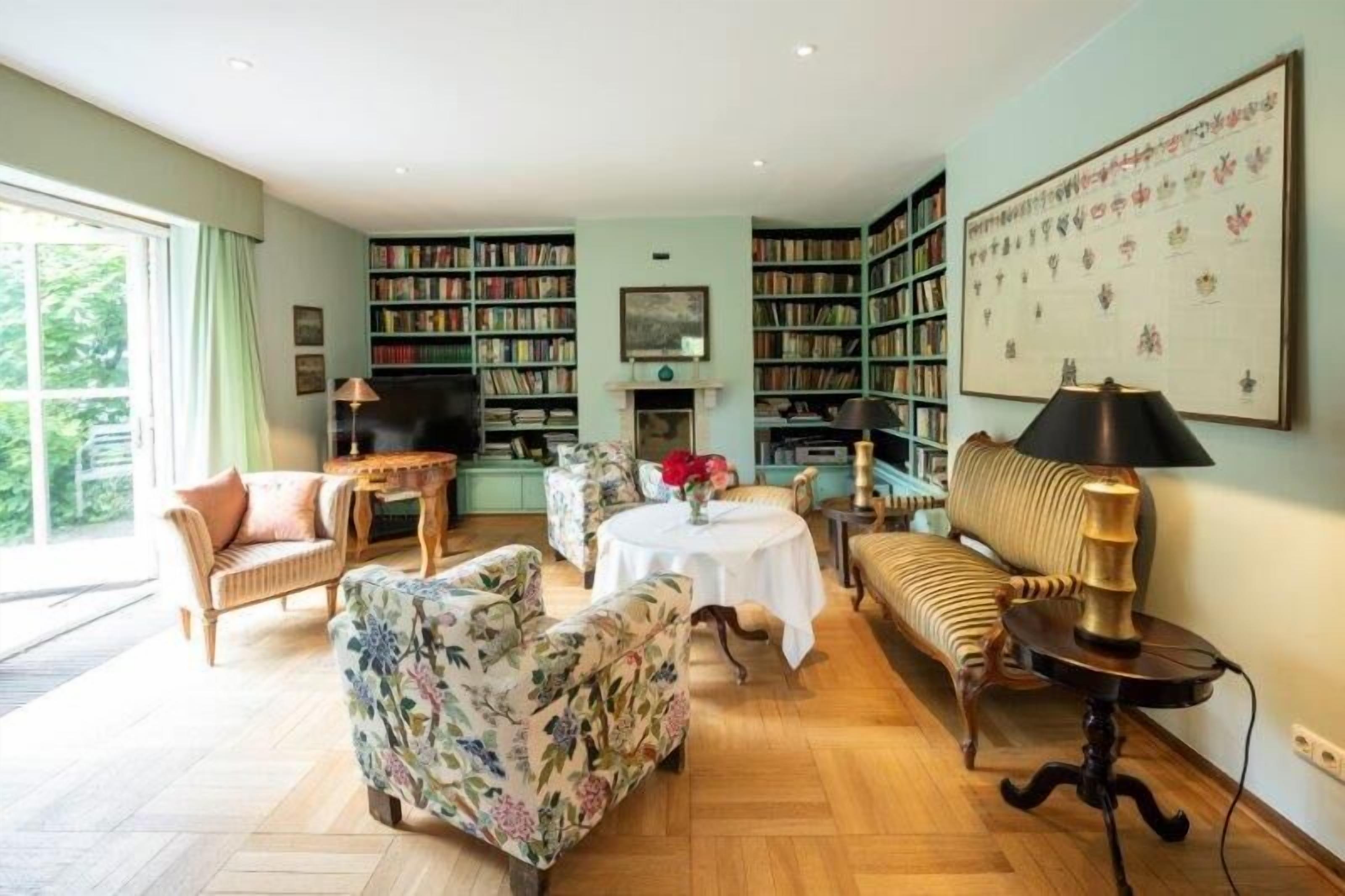 A spacious living room with a fireplace, a large bookshelf, and a dining area.