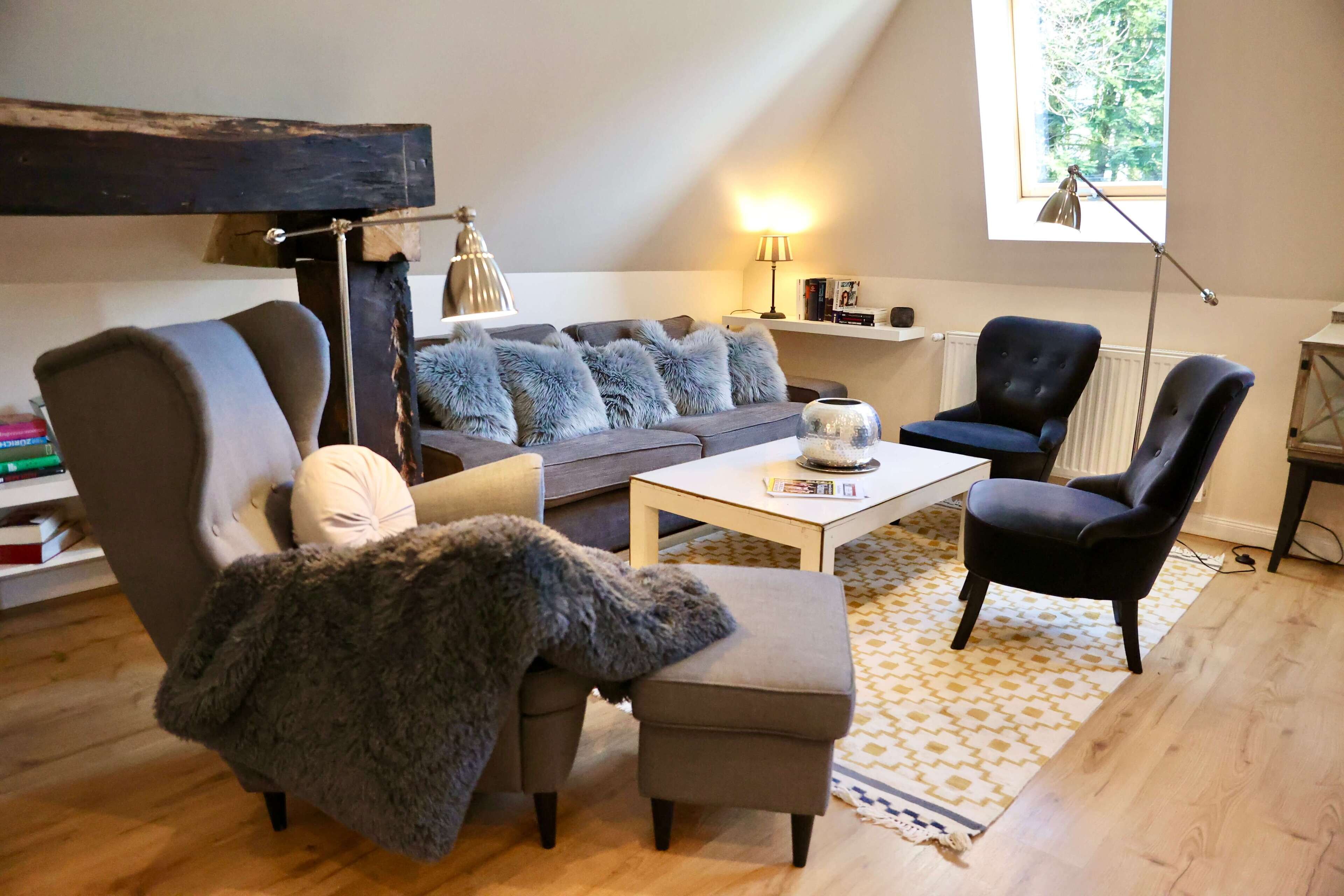 A cozy living room with a sofa, armchairs, a coffee table, and a bookshelf.