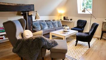 A cozy living room with a sofa, armchairs, a coffee table, and a bookshelf.