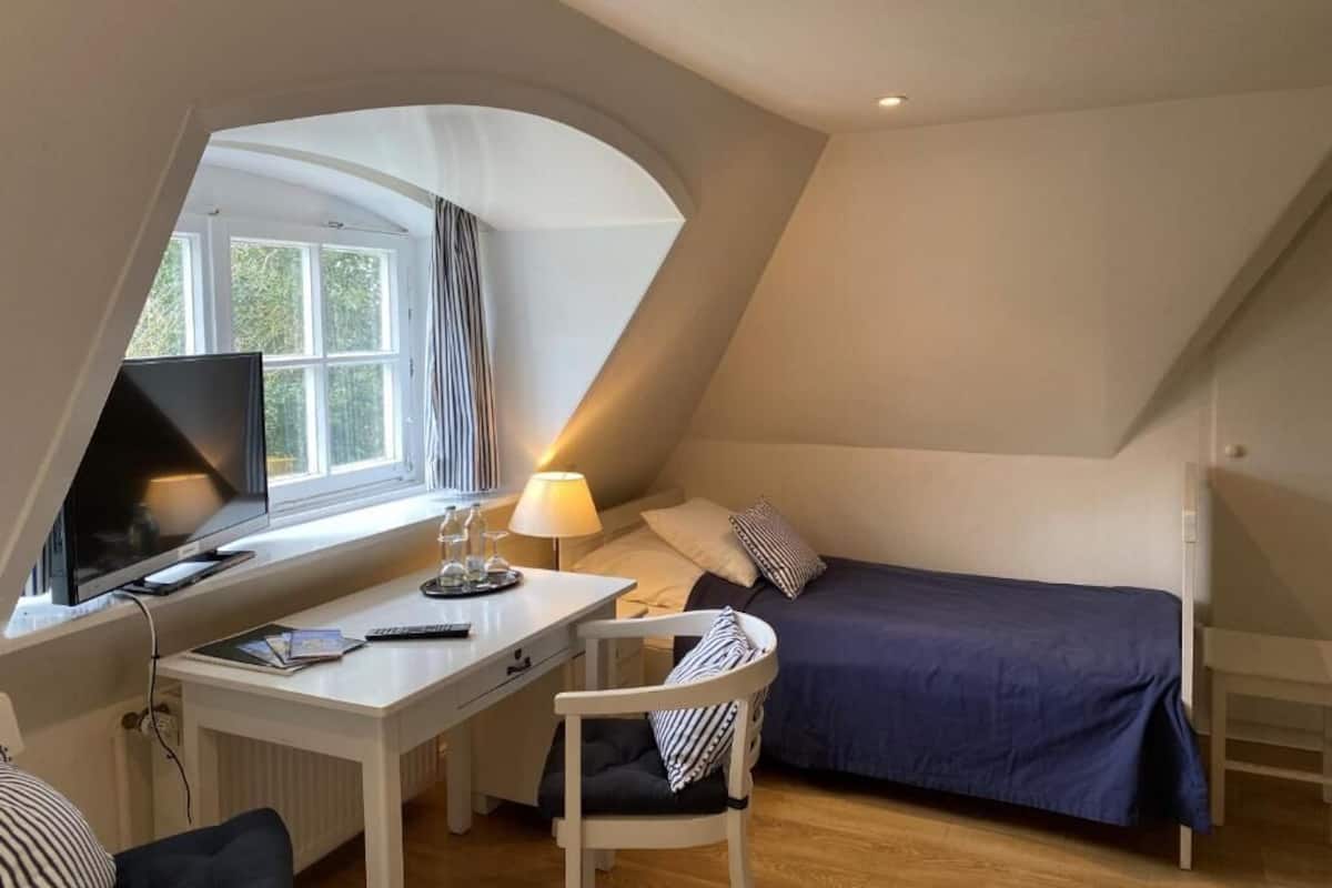 A bedroom with a bed, a desk with a computer, and a chair.