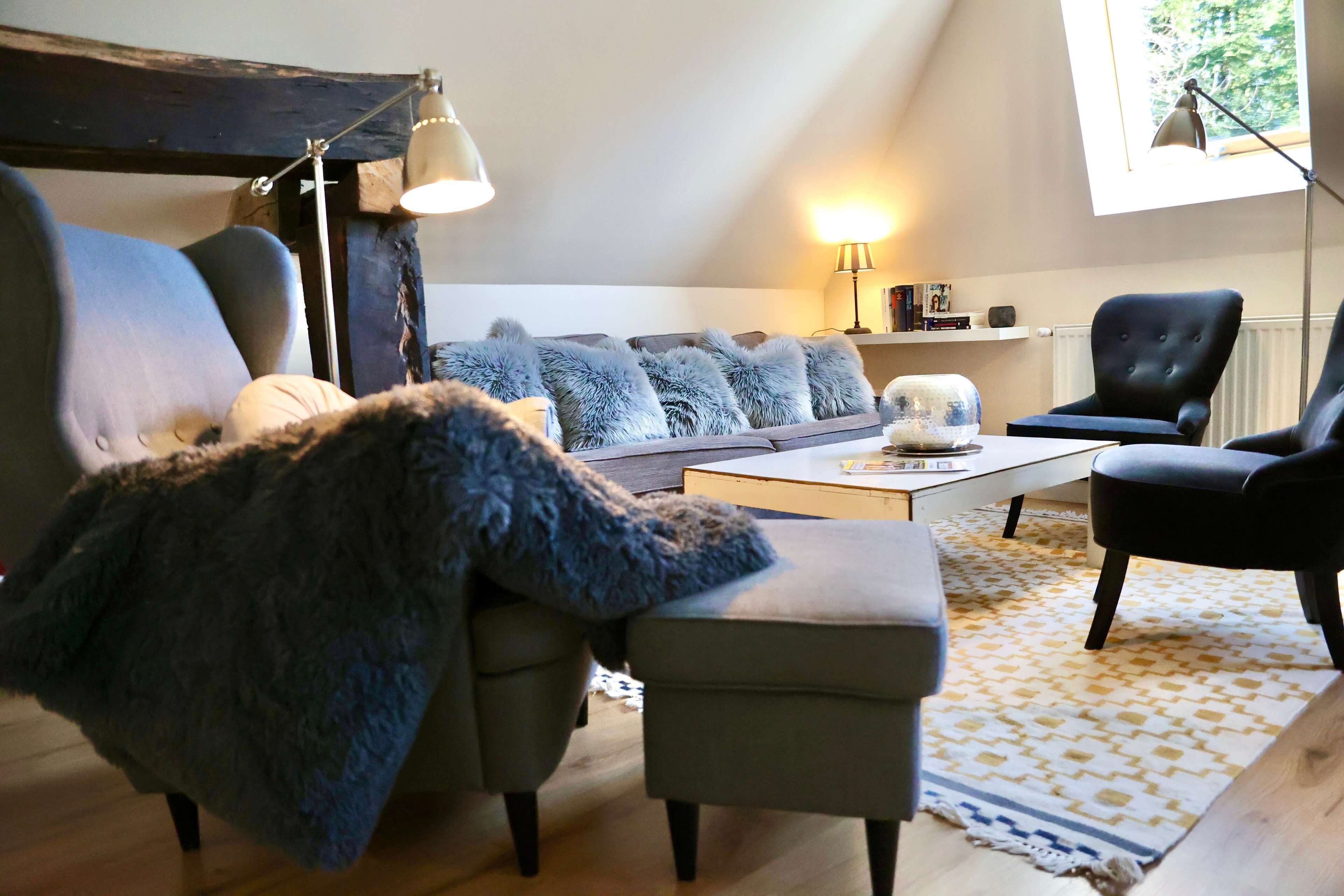A cozy living room with a sofa, armchairs, a coffee table, and a lamp.