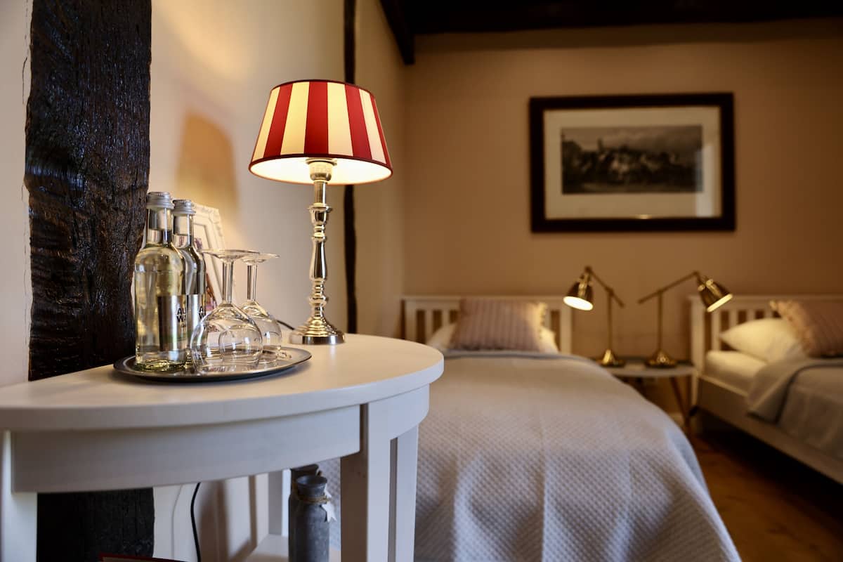 A hotel room with a bed, bedside tables, a lamp, and a framed picture on the wall.