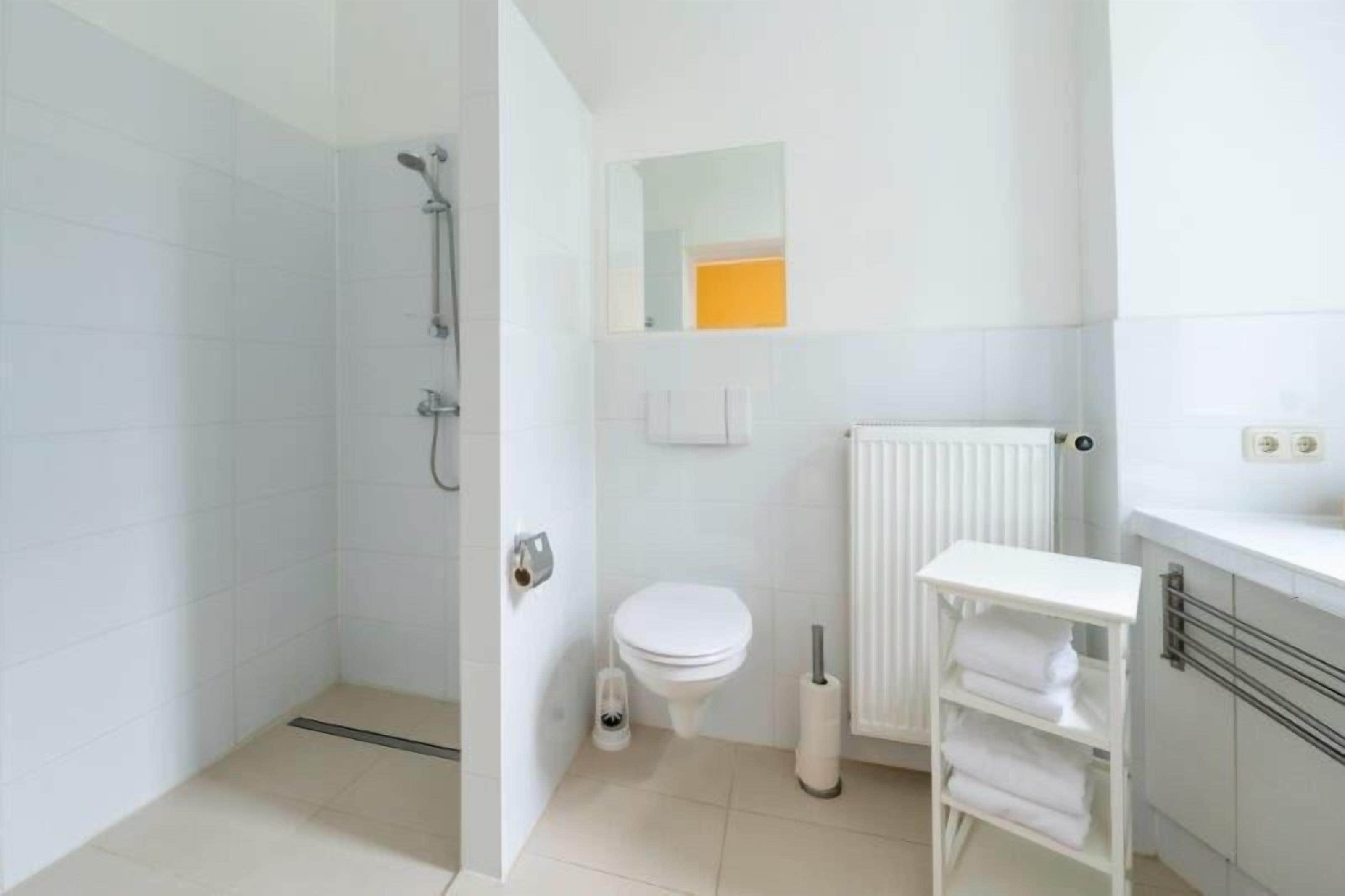 A modern bathroom with a shower, toilet, and a white sink with a towel rack.