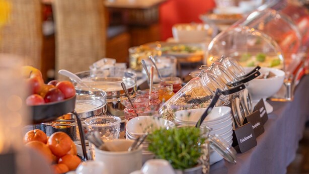 Un buffet proposant une variété d’aliments et d’ustensiles, notamment des fruits, des céréales et un récipient hermétique.