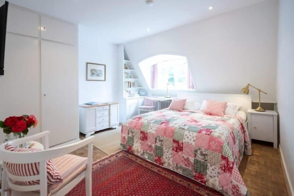A bedroom with a bed, a chair, a desk, and a bookshelf.