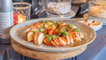 A plate of Caprese salad with tomatoes, mozzarella, and basil on a wooden board.