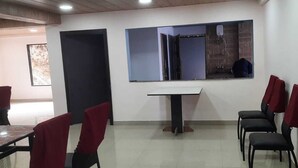 Un salón de conferencias con una mesa blanca, sillas negras y piso de baldosas.