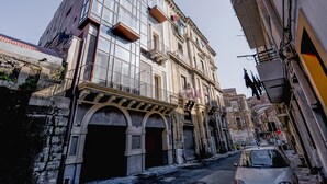 A narrow street with a mix of modern and historic buildings, including a building with large windows and balconies. - Vecchio Bastione Apts by Wonderful Italy (Catania)