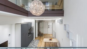 A modern interior with a dining area, kitchen, and a staircase leading to an upper level. - Vecchio Bastione Apts by Wonderful Italy (Catania)