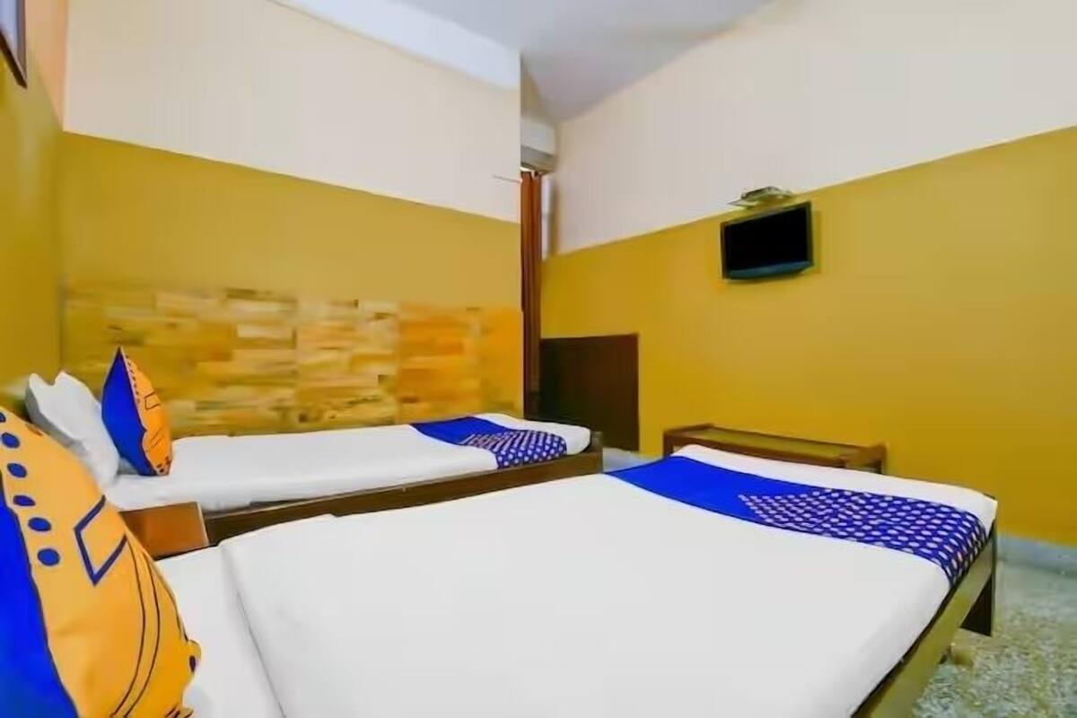 A hotel room with two beds, a stone wall, a small TV, and a wooden door.