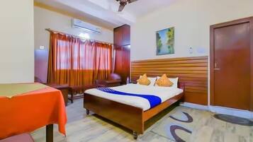 A hotel room with a bed, a table, a ceiling fan, and a door.