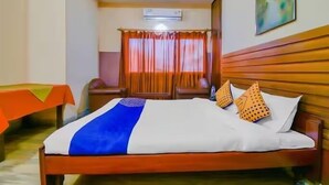 Une chambre d’hôtel avec un lit, une table et une fenêtre avec des rideaux.