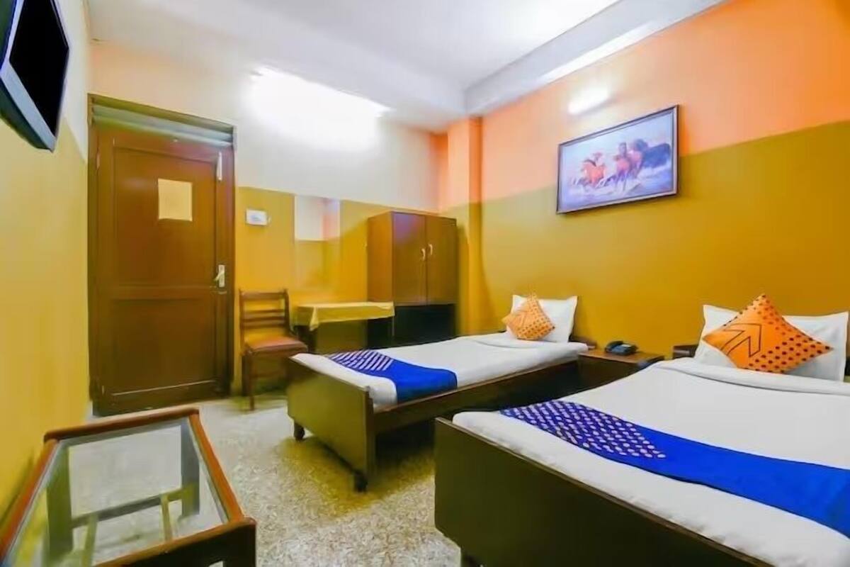 A hotel room with two single beds, a desk, a chair, a wardrobe, and a television.